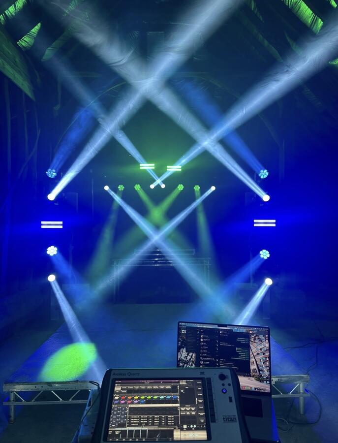 Lighting technician programming beam show in barn venue